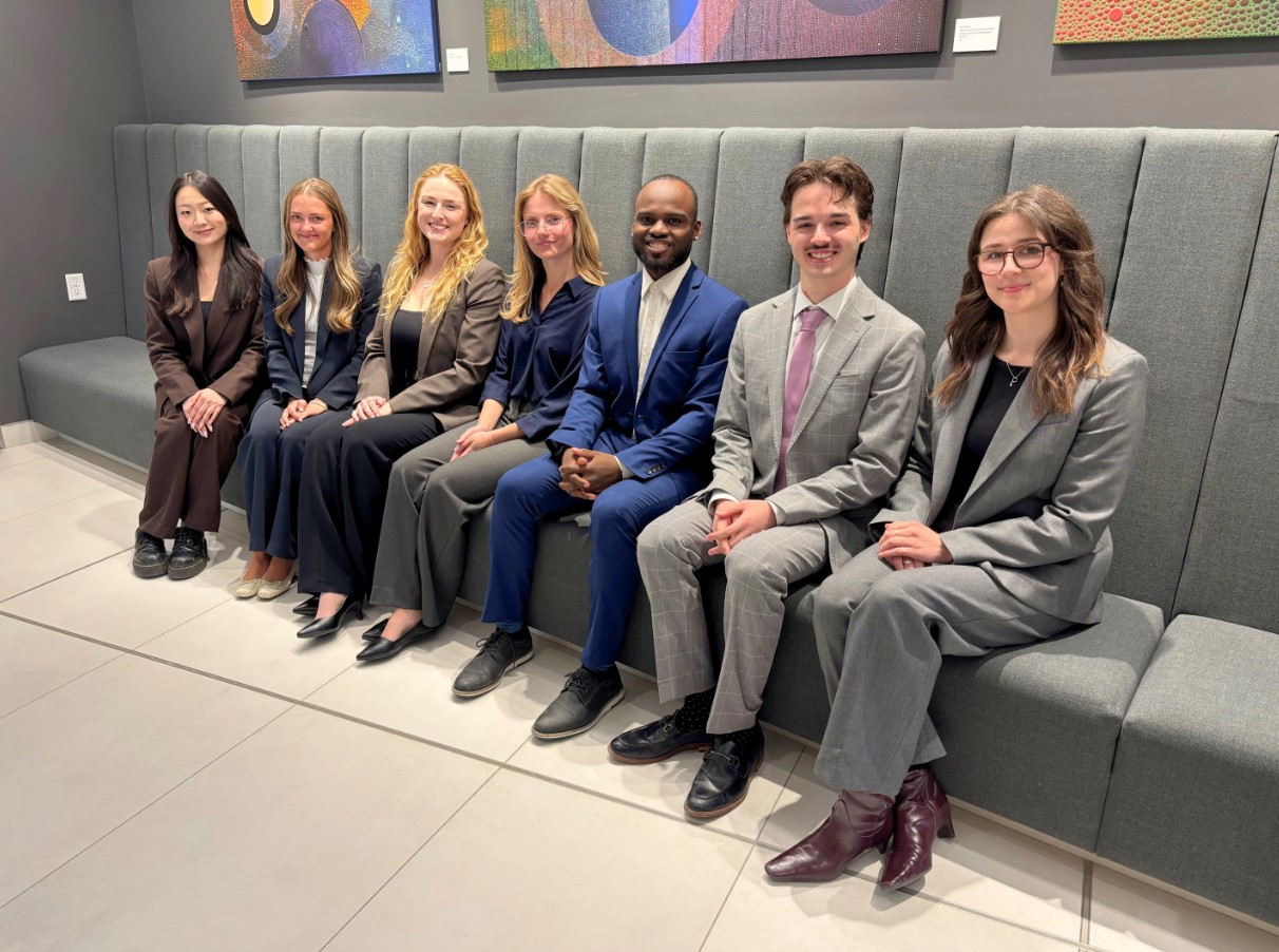 Seven TDS 2026 first-year summer students posing in a professional office setting.